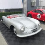 Vintage silver Porsche beside red sports car