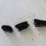 Three black plastic mechanical parts on white surface