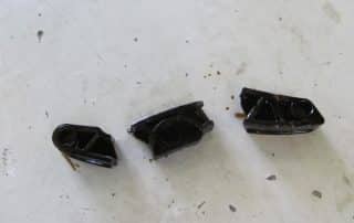 Three black plastic mechanical parts on table