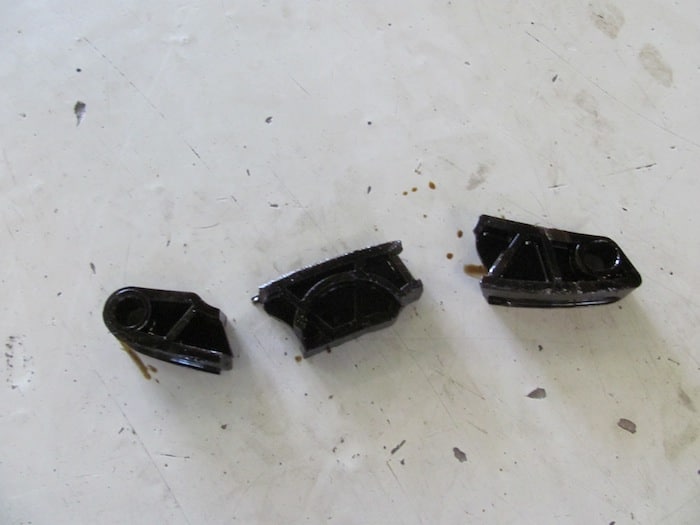 Three black plastic mechanical parts on table