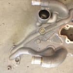 Metal automotive engine component with curved pipes
