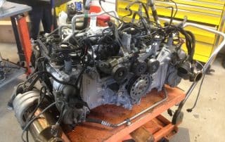 Car engine on workshop cart with tools