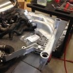 Car engine intake manifold on workshop bench
