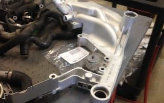 Car engine intake manifold on workshop bench