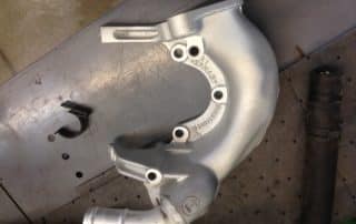 Silver automotive turbocharger housing on workbench