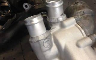Welded aluminum automotive intake manifold on workbench