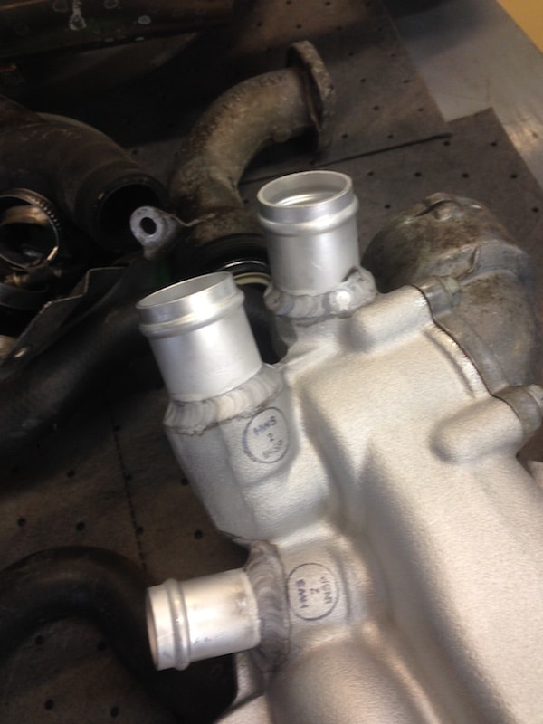 Welded aluminum automotive intake manifold on workbench