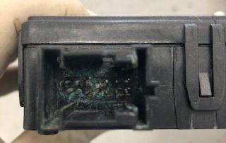 Corroded electronic connector inside black plastic housing