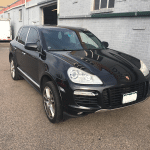 Black Porsche Cayenne parked beside gray building