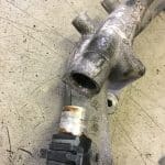 Metal automotive housing with attached sensor on workbench