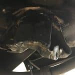 Damaged metal bracket under vehicle chassis