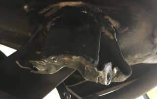 Damaged metal bracket under vehicle chassis