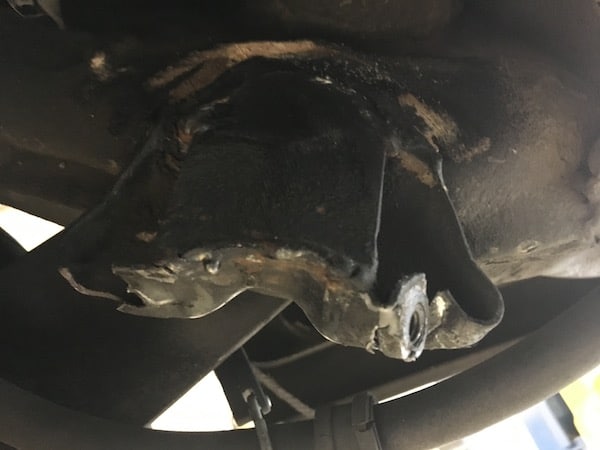 Damaged metal bracket under vehicle chassis