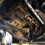 Car underside with oil pan removed in garage