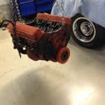 Red engine block suspended by chains in garage