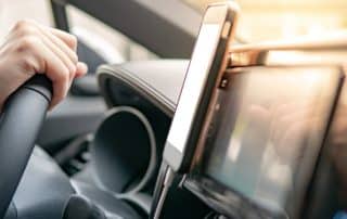 Driver holding steering wheel with smartphone mounted