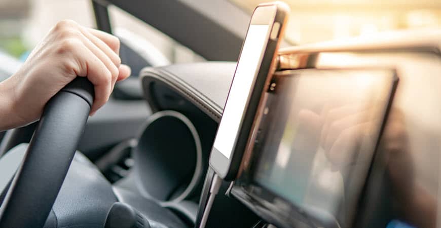 Driver holding steering wheel with smartphone mounted