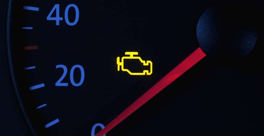 Car dashboard with illuminated check engine light