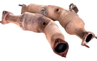 Two rusty catalytic converters on white background