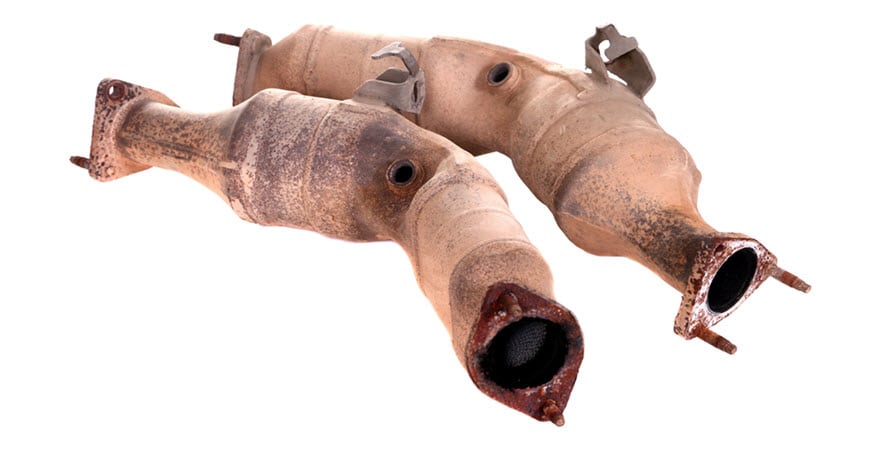 Two rusty catalytic converters on white background