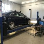 Black sedan on lift in auto shop