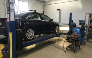 Black sedan on lift in auto shop
