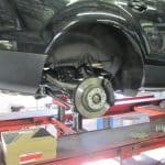 Car on lift with wheel removed in garage