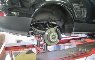 Car on lift with wheel removed in garage