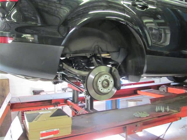 Car on lift with wheel removed in garage