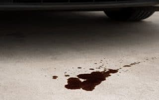 Dark fluid puddle under parked car