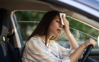 Woman holding tissue to forehead while driving car