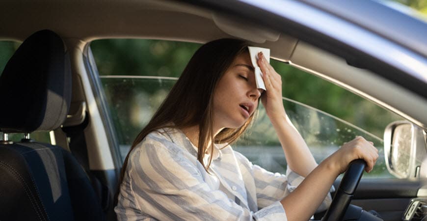 Woman holding tissue to forehead while driving car
