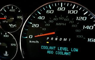 Car dashboard displaying low coolant warning message