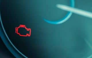 Car dashboard with illuminated check engine warning light