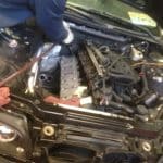 Person repairing car engine under open hood