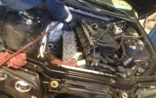 Person repairing car engine under open hood