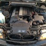 Open BMW engine bay with headlights on