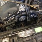Car engine bay with exposed belts and pulleys