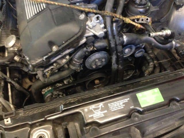 Car engine bay with exposed belts and pulleys