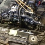 Car engine bay with exposed belts and hoses