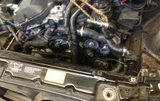 Car engine compartment with exposed belts and hoses