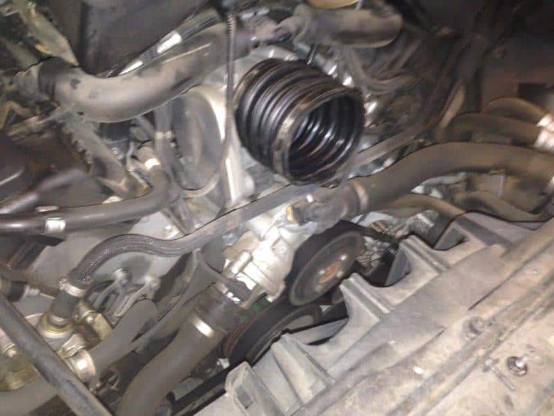 Car engine bay with exposed belts and hoses