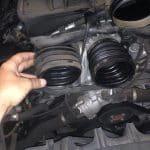Hand holding rubber intake hose in car engine