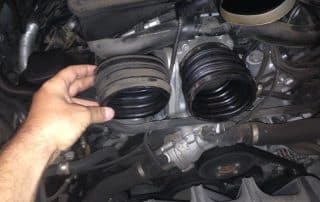 Hand holding disconnected rubber intake hose in engine