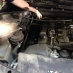 Person inspecting car engine under open hood