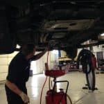 Mechanic draining oil from car on lift