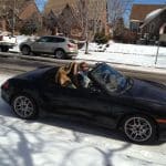Black convertible driving on snowy residential street