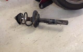 Car suspension strut with coil spring on floor