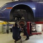 Mechanic repairing car brake on lifted vehicle