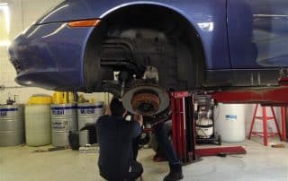 Mechanic repairing car brake on lifted vehicle